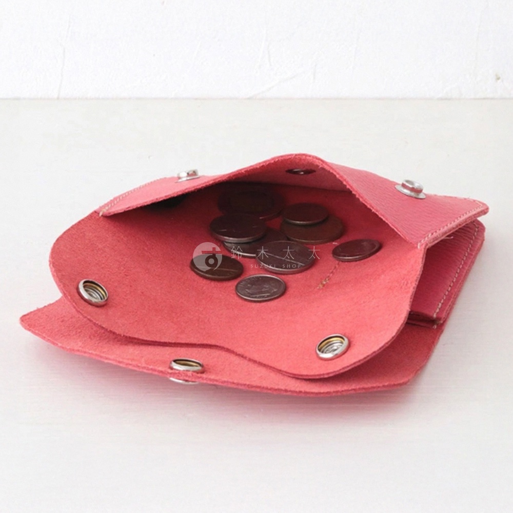 桃紅色皮革零錢包，內部裝有硬幣，以側邊角度拍攝，展示其柔軟的皮革材質與金屬按扣設計。