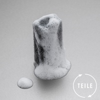 一塊黑色超細纖維海綿，表面覆蓋著豐盈的白色泡沫，旁邊有一小攤泡沫。