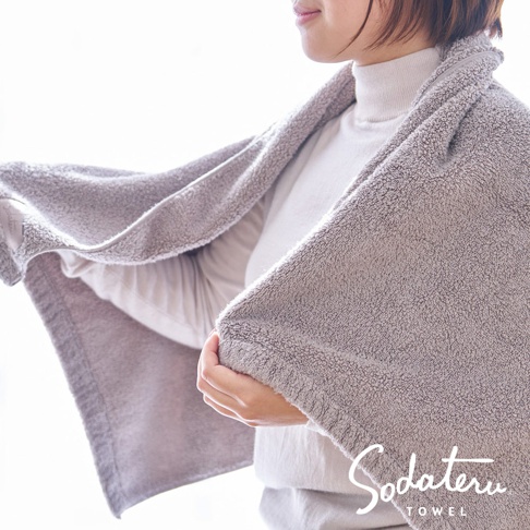 灰色毛圈浴巾，柔軟蓬鬆，材質輕盈，觸感細緻，一角有品牌Logo。