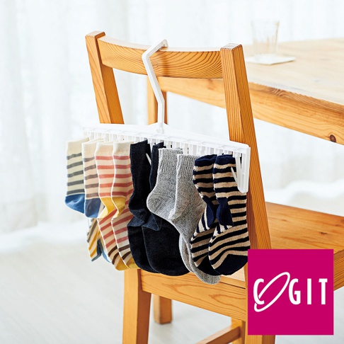 白色塑膠晾衣夾，掛有十雙不同花色、材質的襪子，包括條紋、純色等，夾子上方有掛鉤，懸掛於木椅上。
