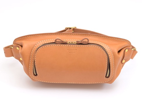 棕色皮革製成的職人手作斜背包，具有拉鍊開口和精緻縫線細節。