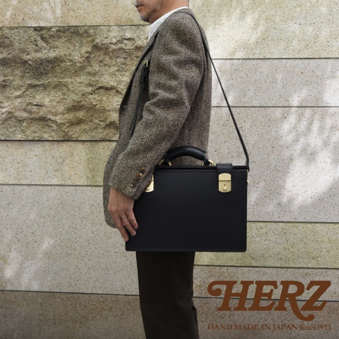 職人手作皮革兩用機師箱，黑色，配有金色鎖扣和手柄，可肩背或手提。