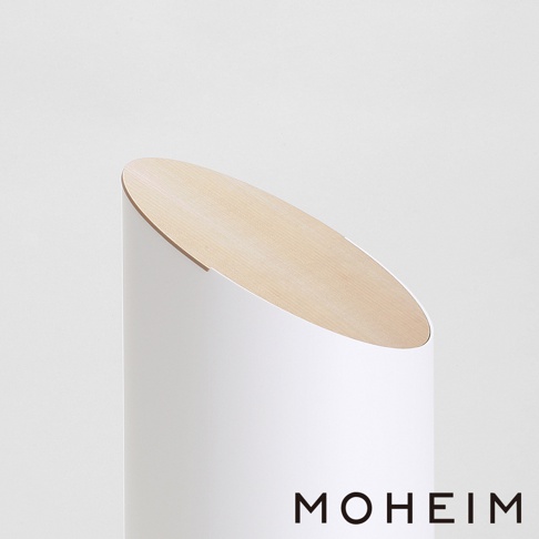 白色圓柱形垃圾桶，頂部有傾斜的淺木色木蓋，品牌名稱「MOHEIM」以黑色字母顯示於下方。