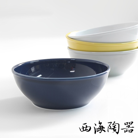 波佐見燒 Common 陶瓷料理深碗，深藍色，15公分。碗身圓潤，邊緣帶有細緻的藍色滾邊。後方堆疊著黃色、白色和淺灰色的同款陶瓷碗。
