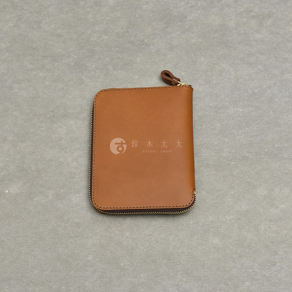 職人手作皮革Organ記事本收納包，採用棕色皮革製成，拉鍊開合設計，正面印有SUZUKI SHOP的標誌。
