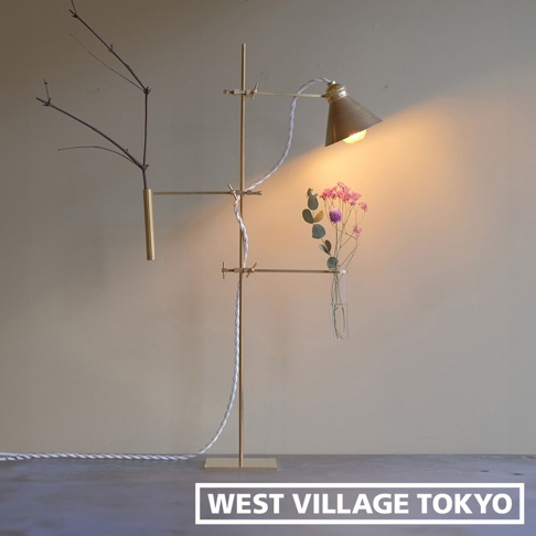 黃銅材質的燈具展示架，高度約 60 公分，設有可調節的支架，可懸掛一個黃銅花瓶和一個玻璃試管花瓶，分別裝飾著枯枝和粉色小花。