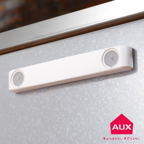 白色長條形收納袋架，兩端各有一個透明圓形夾口，架身使用塑膠材質，以吸盤固定在灰色紋理背景上。