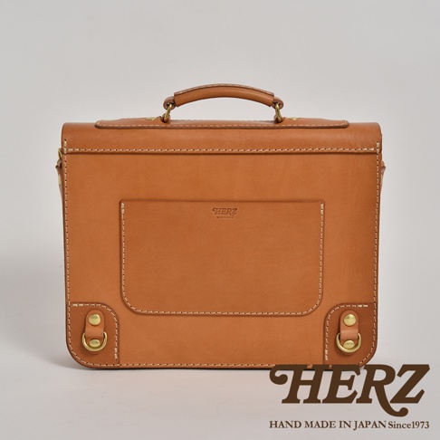 職人手作淺棕色皮革歐風三用學生包，帶有精緻縫線、金屬扣環和頂部提把，正面有品牌壓紋和置物袋。