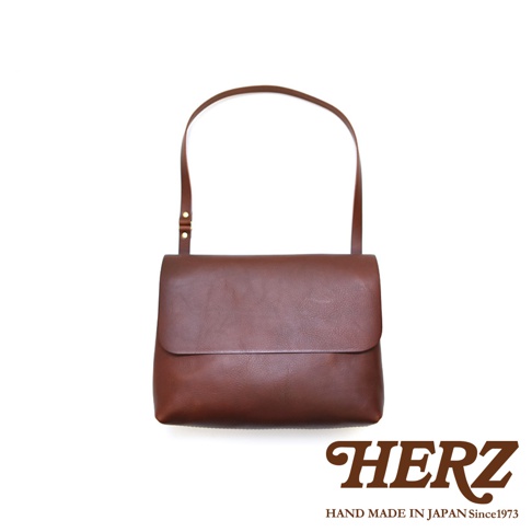 職人手作皮革經典郵差包 CK-4 M，採用厚實的皮革材質，呈現自然紋理，為棕褐色調。包款設計簡約，翻蓋式開口，搭配可調節長度的細肩帶，適合斜背或單肩背。