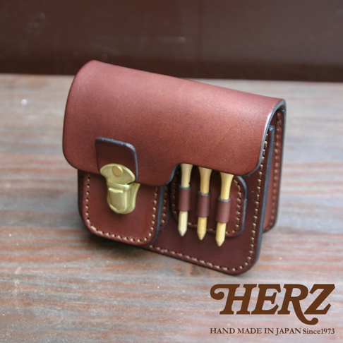 職人手作皮革高爾夫腰包，深棕色，附黃銅扣環，側面有三個高爾夫球釘插槽，展現精緻縫線工藝。