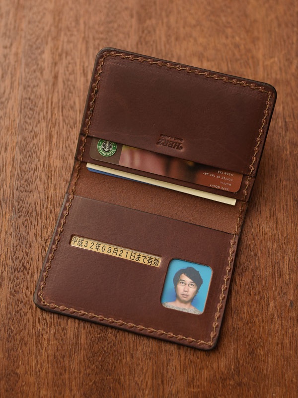 職人手作皮革雙折證件收納夾，深棕色皮革，手工縫線，內含卡片插槽、證件照窗及日文標示「平成32年08月21日まで有効」。