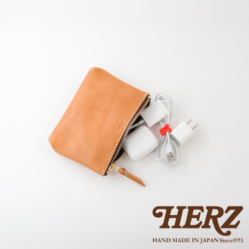 職人手作皮革長方形拉鍊收納包，淺棕色，內部裝有白色耳機和充電器。