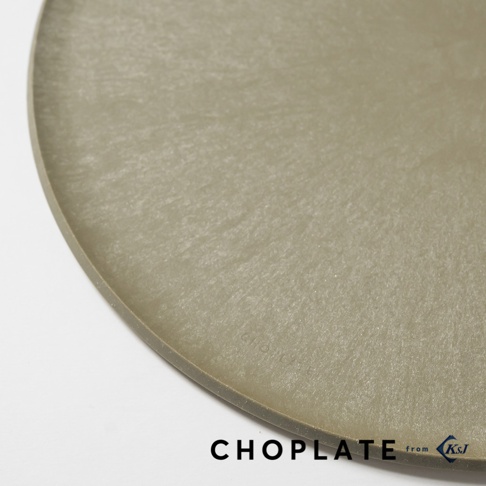 這是一張近距離俯拍的淺灰色 CHOPLATE 兩用砧板盤局部特寫，盤面呈現細緻的霧面紋理與圓弧邊緣，右下角印有 CHOPLATE 品牌標誌與 KSJ 字樣，整體設計簡約現代。