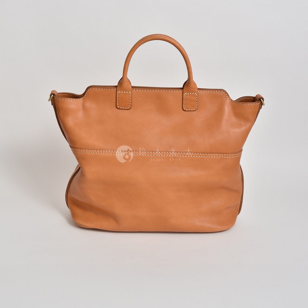 棕色皮革製成的兩用托特包，有著圓潤的提把和手工縫線，包身寬大，可容納多樣物品。