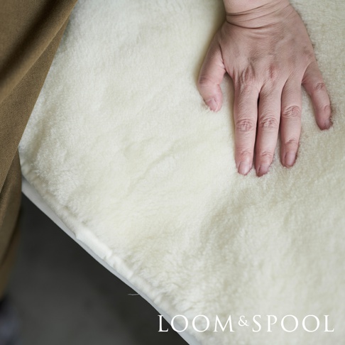 單人美麗諾羊毛厚感保暖墊，奶油白色，觸感柔軟蓬鬆，展示了其保暖材質的質感。