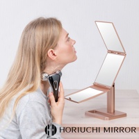 玫瑰金色三折式桌上化妝鏡，鏡架為金屬材質，展開後可見三面鏡子，適合用於臉部美容保養。