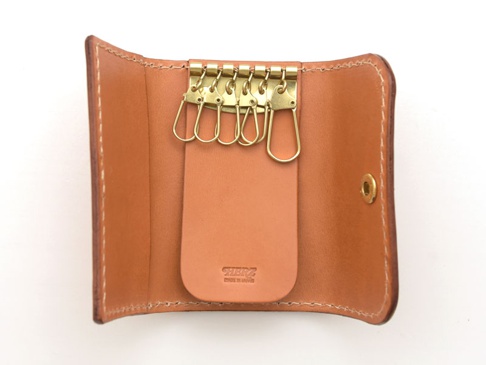 棕色皮革鑰匙包，內有六個金色金屬鑰匙鉤，中央皮革片上有壓印品牌標誌。