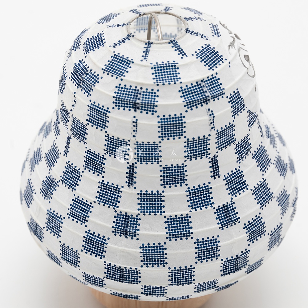 白色紙質達摩不倒翁造型提燈，表面印有藍色細點組成的棋盤格圖案，頂部有金屬提環，下方為木質底座。