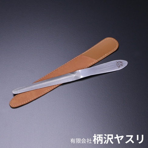 曲面極細高碳鋼銼刀，刀身為銀色金屬材質，帶有細緻的銼紋，末端有品牌標誌。銼刀置於淺棕色皮革護套上，護套邊緣有縫線。