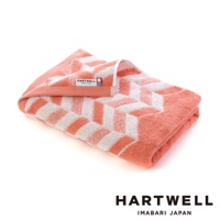 一條珊瑚粉色與白色相間的今治毛巾，以傳統和風幾何紋樣織成，材質柔軟，帶有品牌標籤。
