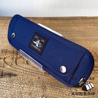 一個深藍色純棉帆布製成的長方形收納包，表面縫有黑色標籤，標籤上有日文圖案和文字。收納包側邊有金屬釦，整體呈現堅固耐用的質感。