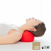 一位女性仰躺，頭部下方襯著一個紅色的指壓按摩枕，枕頭呈現圓潤的球狀，材質看起來柔軟。