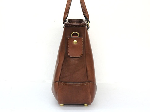 職人手作皮革兩用商務托特包，採用棕色光滑皮革製成，側面可見金屬扣環和縫線細節，包包底部配有四個金色金屬腳釘。