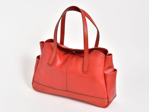 紅色皮革橫式肩背托特包，帶有兩個側邊口袋和頂部提把，包身縫線清晰，材質光滑。