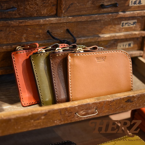 職人手作皮革L型拉鍊迷你短夾，展示橘色、橄欖綠、棕色和焦糖色共四款顏色。短夾採用皮革材質，具有L型拉鍊設計，縫線清晰。