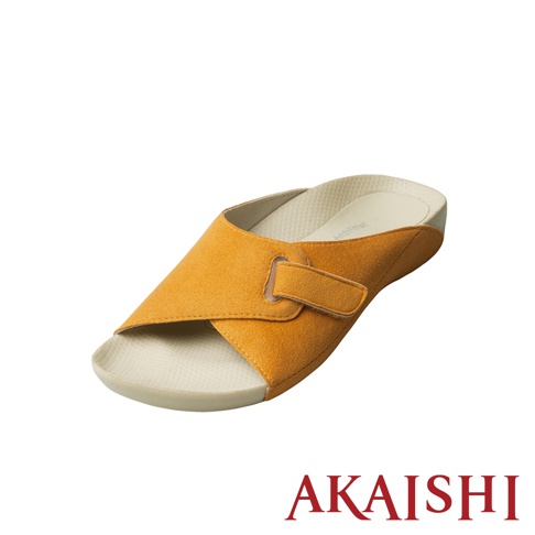 一隻橘黃色麂皮材質的指壓室內拖鞋，鞋面為交叉設計，搭配可調節的魔鬼氈袢，鞋墊為米白色，鞋底為淺灰色。