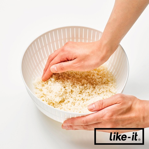 白色簡約雙層瀝水籃，籃身有多孔設計，籃內裝有米粒，兩隻手正在清洗米粒。