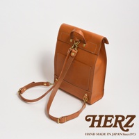 職人手作皮革紙袋風後背包，採用光滑的棕褐色皮革製成，配有可拆卸的肩帶和金色金屬配件。