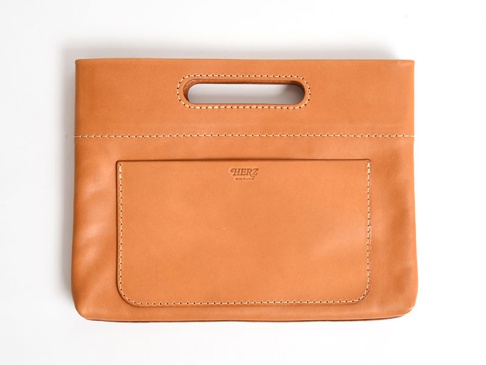 職人手作皮革橫式收納袋，卡其色，天然皮革材質，正面有一個方形外袋，袋口上方有提把，縫線清晰。