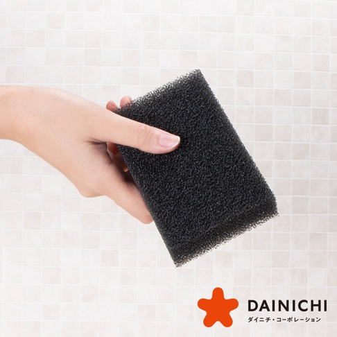 手持黑色長方形海綿，海綿材質為細緻的發泡結構，背景為淺色馬賽克磁磚。