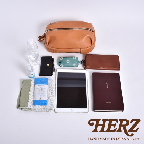 HERZ 職人手作皮革立體運動斜背包 F-9，內容物包含一個淺棕色立體皮革包，搭配品牌 logo。