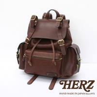 職人手作棕色皮革復古旅行後背包，帶有金屬扣環和抽繩閉合，側面有兩個小口袋，整體呈現經典復古風格。