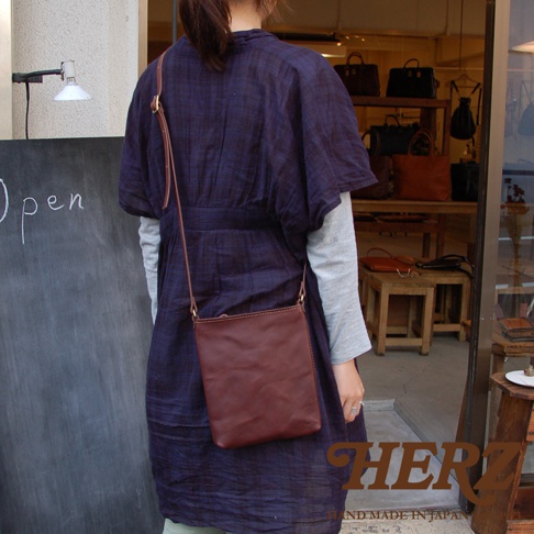 職人手作皮革Organ肩背小方包，採用酒紅色皮革製作，方形簡約設計，搭配細長肩帶，可斜背或肩背。