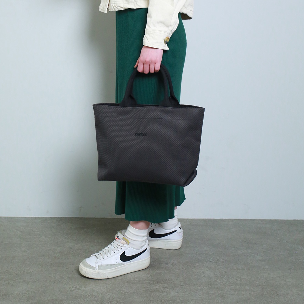 深灰色三河木綿刺子織托特包，配有黑色提把，包身有細緻的菱形紋理，中央有品牌 Logo。