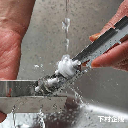 一隻手拿著不鏽鋼磨刀器，其上裝有兩個白色滾輪，正被沖洗。