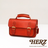 職人手作皮革雙扣兩用迷你肩背包，採用紅色皮革，設有金色搭扣和頂部提把，風格簡潔。