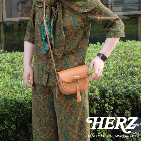 棕色皮革流蘇側背包，配有繫繩開口和流蘇裝飾。包包的肩帶也是皮革材質。