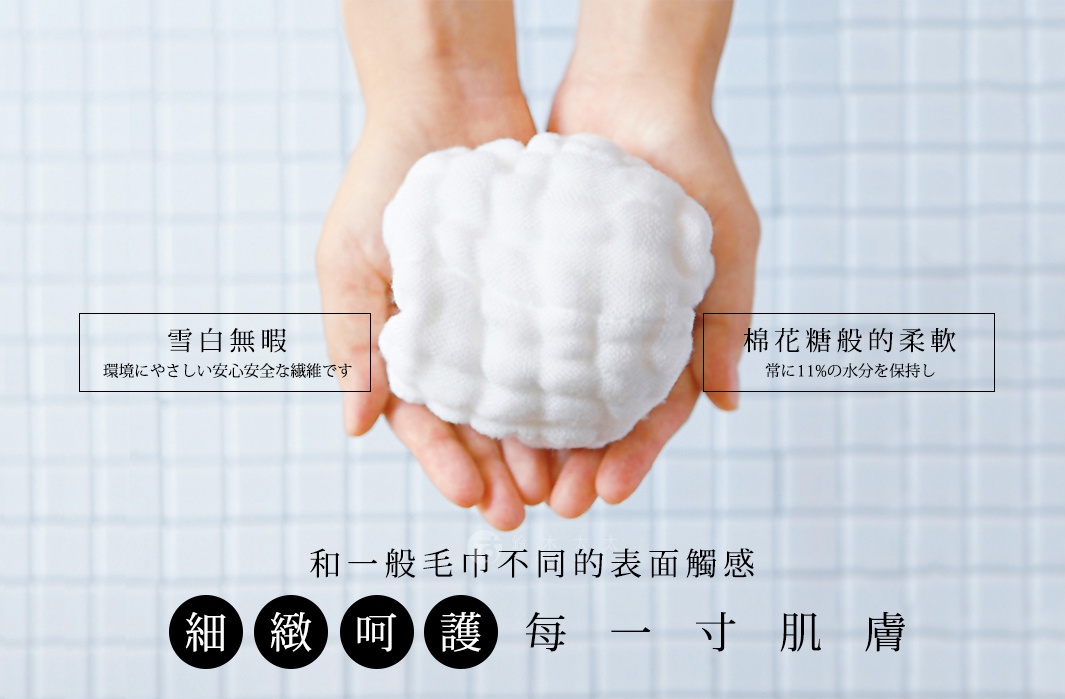 雙手捧著一團蓬鬆的白色毛巾，左側文字「雪白無瑕，環境やさしい安心安全な繊維です」，右側文字「棉花糖般的柔軟，常に11%の水分を保持し」，下方文字「和一般毛巾不同的表面觸感，細緻呵護每一吋肌膚」。