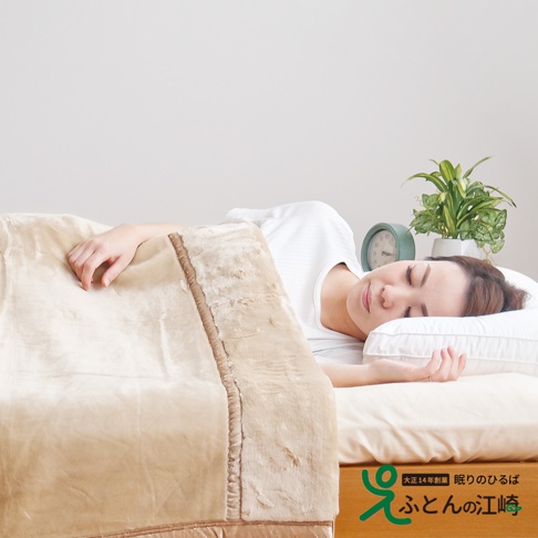 一位女性躺在床上，蓋著一條米白色的加厚柔暖毯，毯子邊緣有絨毛飾邊。