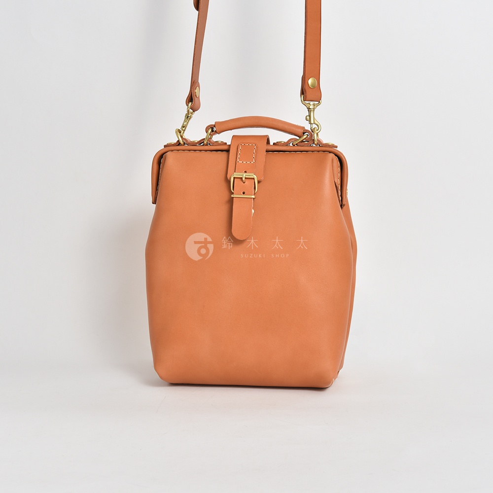 職人手作皮革迷你軟皮杜勒斯包，採用天然皮革製成，經典的馬鞍棕色，搭配金色金屬扣環和可調節的肩帶。包身線條流暢，設計簡約，適合日常搭配。