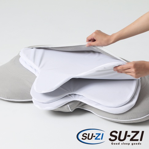 一隻手正在拉開一個淺灰色側睡止鼾枕的外層白色網狀布套，露出內層白色網狀材質，枕頭整體呈淺灰色。