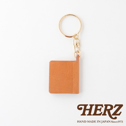 職人手作皮革書本造型鑰匙圈，採用質感棕色皮革製成，搭配金色鑰匙圈與扣環，造型精巧。