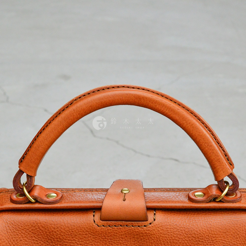 職人手作皮革Organ方形口金托特包，展示包款的提把、金屬扣環與皮革材質，呈現溫潤的棕色調。