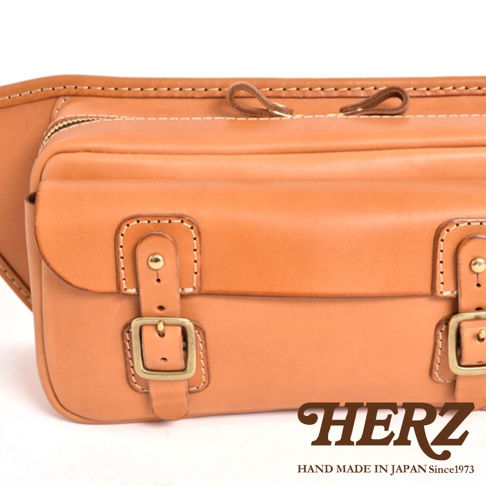 簡約風格的棕色皮革斜背包，採用精緻縫線和金屬釦環設計，展現職人手作質感。