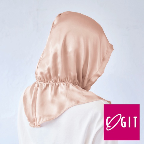 淺膚色絲質柔亮美髮晚安睡帽，採用光滑綢緞材質，頭部為圓弧形設計，領口處有鬆緊帶收邊，背面露出部分白色衣物。