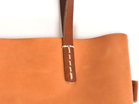 職人手作皮革直式軟皮托特包，採用光滑的駝色皮革，搭配咖啡色皮革提把，以白色縫線加固。
